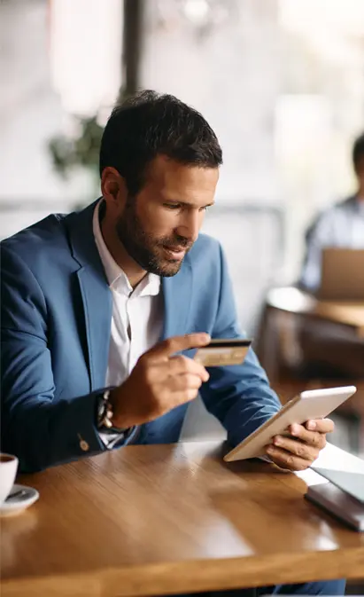 A man holding a credit card in front of a tablet